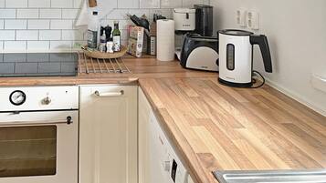 Una cocina con estufa blanca, encimera de madera, cafetera Bosch y un lavabo.