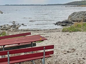 Een strand met een rode bank en een rotsachtige kustlijn.