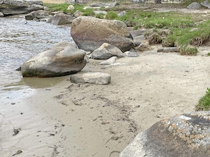 Un paisaje natural con un río, rocas grandes y zonas cubiertas de hierba.