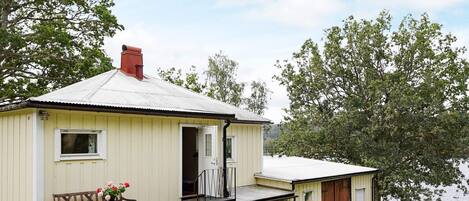 A small, single-story building with a sloped roof, a front door, and a small porch area.