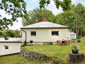 A single-story house with a sloped roof, a small porch, and a stone wall in the foreground. - 5 Person Holiday Home in Bullaren (Bullaren)