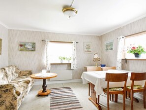 A cozy living room with a sofa, a round wooden table, a dining table with chairs, and a window with curtains. - 5 Person Holiday Home in Bullaren (Bullaren)