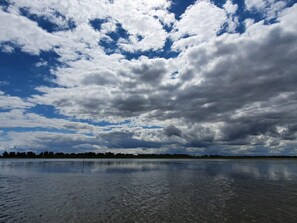 A body of water reflecting clouds, with a distant tree line.