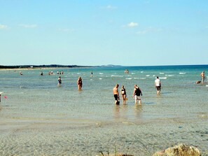 A beach with people in the water and on the shore, clear skies, and distant land. - 5 Star Holiday Home in Hadsund (Hadsund)