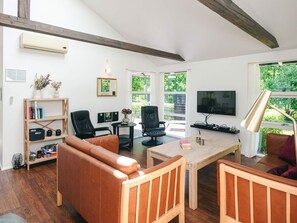 Un salon moderne avec un plafond en bois, un canapé, une table basse et un téléviseur.
