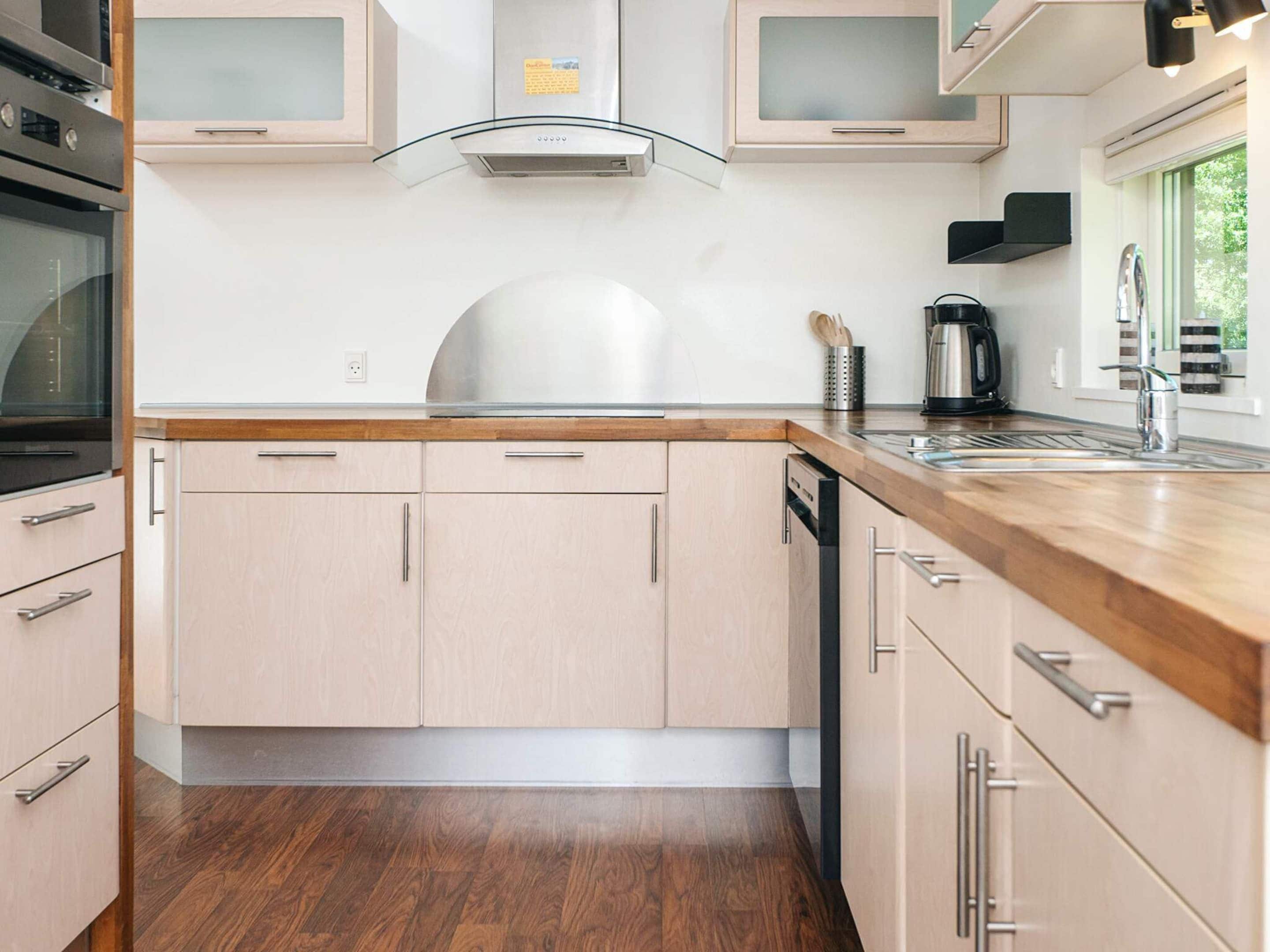 Een moderne keuken met houten kastjes, een roestvrijstalen afzuigkap en een inbouwvaatwasser.