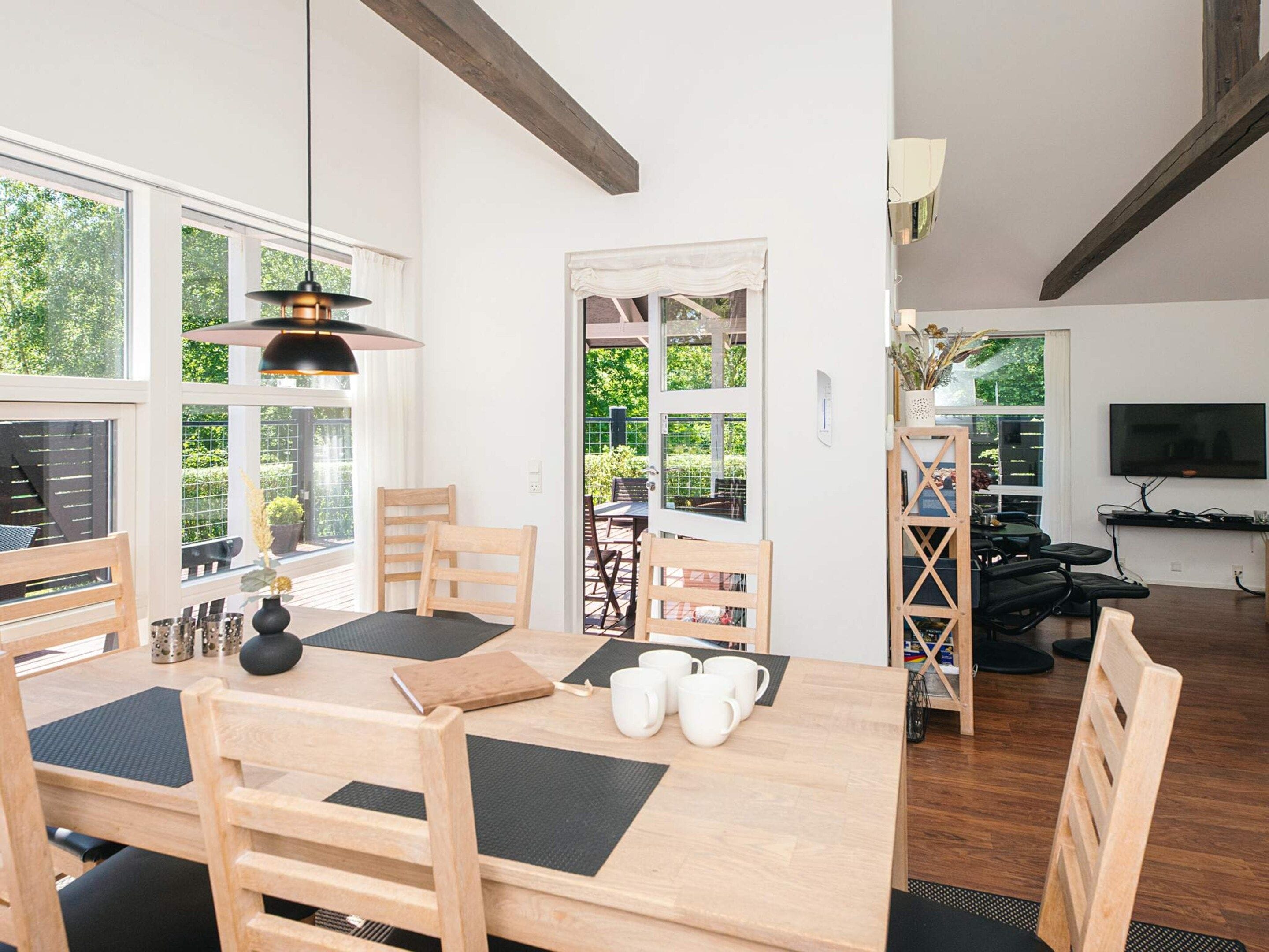 A dining area with a wooden table, chairs, and a hanging light fixture.