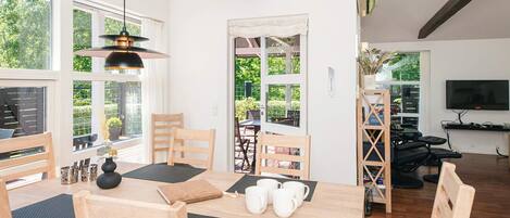 A dining area with a wooden table, chairs, and a hanging light fixture.