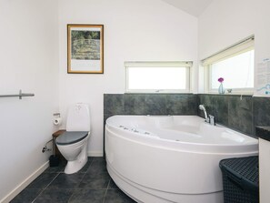 A modern bathroom with a toilet, a bathtub, and a window.