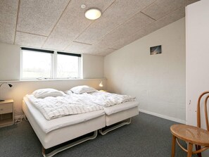 A bedroom with a bed, bedside lamps, a window, and a chair. - 4 Star Holiday Home in Logstor (Logstor)
