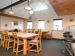 A room with a high ceiling, wooden tables and chairs, and large windows. - 4 Star Holiday Home in Logstor (Logstor)