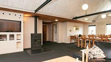 Una sala moderna con chimenea, un televisor de pantalla plana y un comedor con mobiliario de madera.