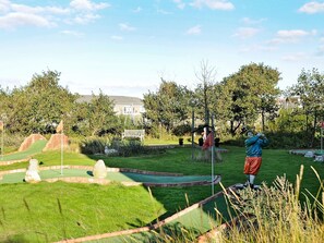 A miniature golf course with a statue, a bench, and a flag.