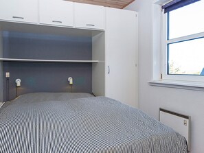 A bedroom with a bed, built-in wardrobe, bedside lamps, and a window. - 6 Person Holiday Home in Fano (Fano)