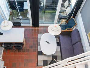 Een modern terras met zitplaatsen, een tafel en stoelen, een bank en een kleine ronde tafel met een afstandsbediening.