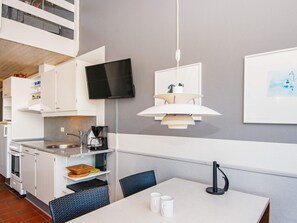 A modern kitchen with a flat-screen TV, a coffee maker, and a dining area with a table and chairs.
