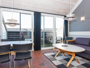 Un intérieur moderne comprenant un coin repas, un canapé et de grandes fenêtres.