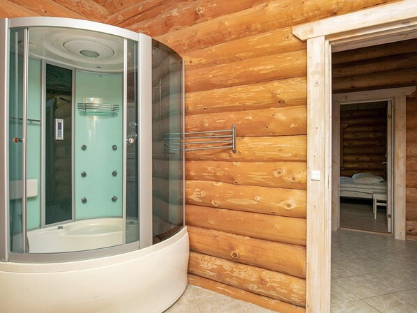 A modern bathroom with a glass-enclosed shower, a visible control panel, and a wooden cabin interior.