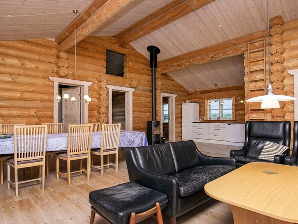 A log cabin interior with a dining area, a sofa, and a kitchen.