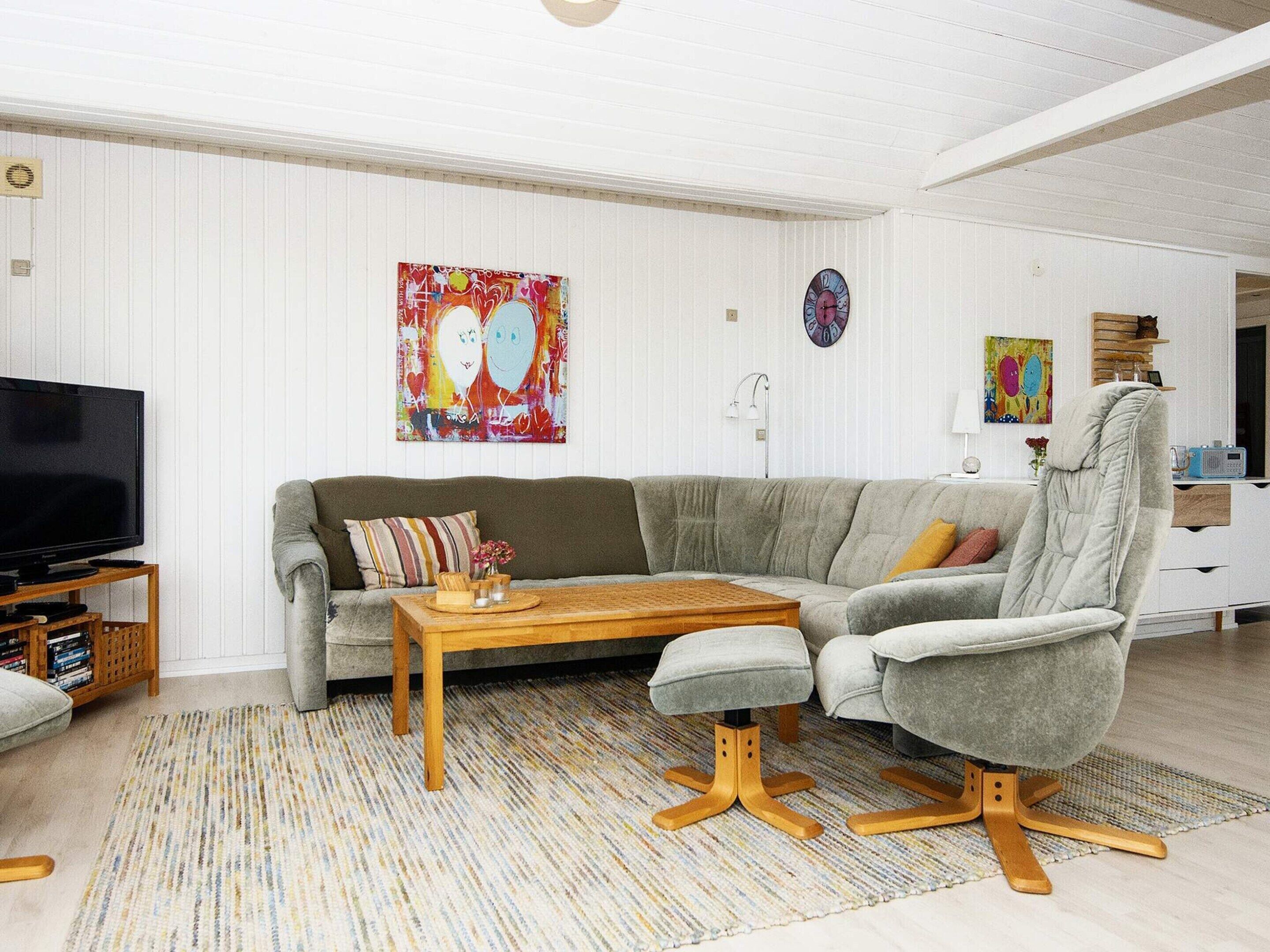 Un salon comprenant un canapé, une table basse, un téléviseur et des œuvres d’art accrochées aux murs.