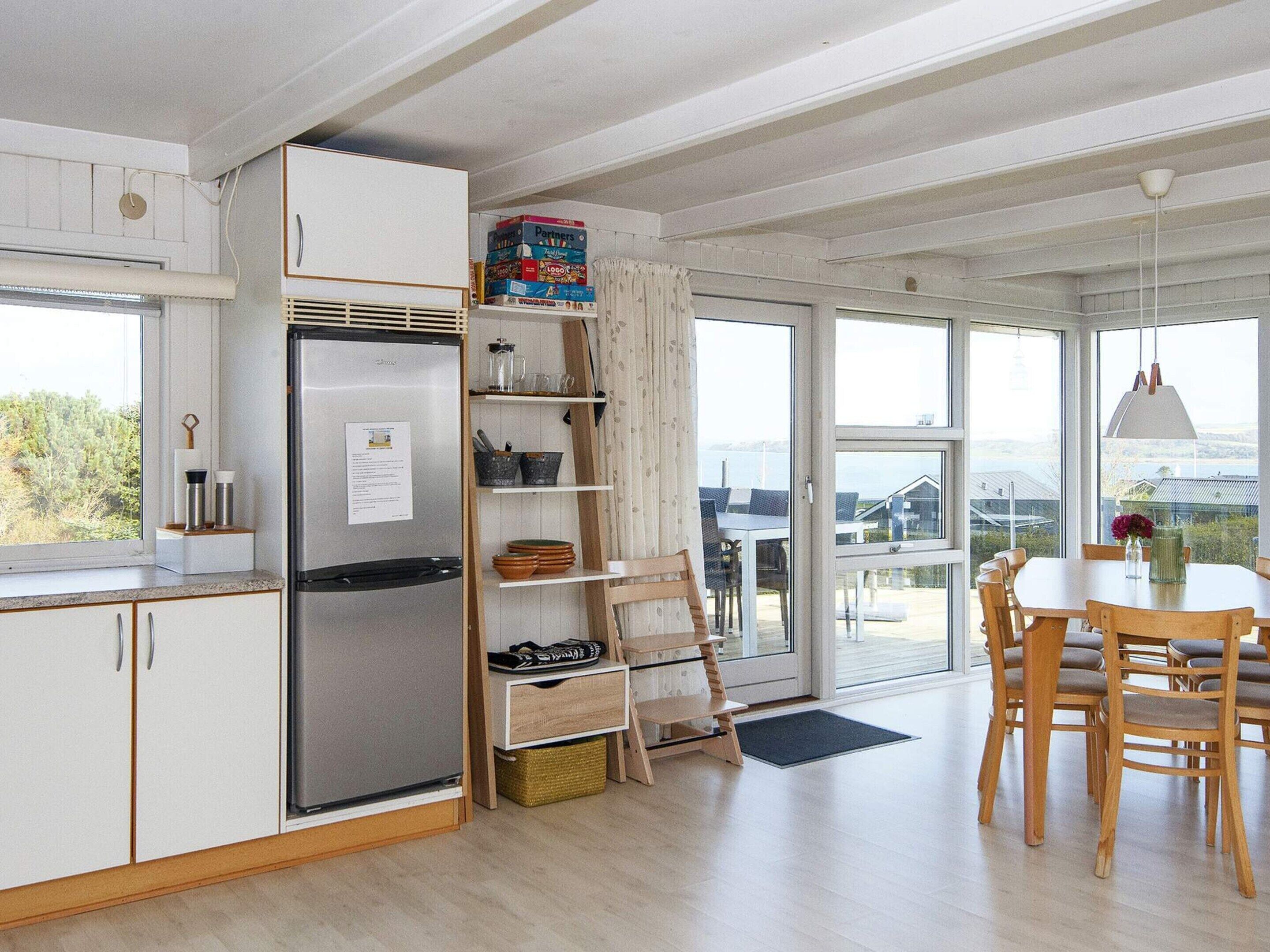 A modern kitchen with a built-in refrigerator, wooden cabinets, and a dining area with a table and chairs.
