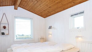 A bedroom with a wooden ceiling, a bed with white bedding, a window, and a small bedside table. - 4 Star Holiday Home in Lemvig (Lemvig)