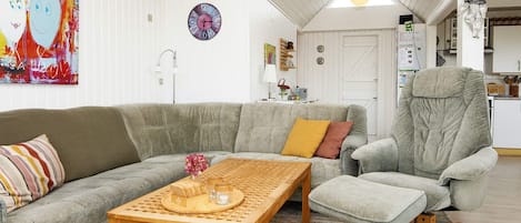 Ett vardagsrum med en soffa, en fåtölj, ett soffbord och en tavla på väggen.