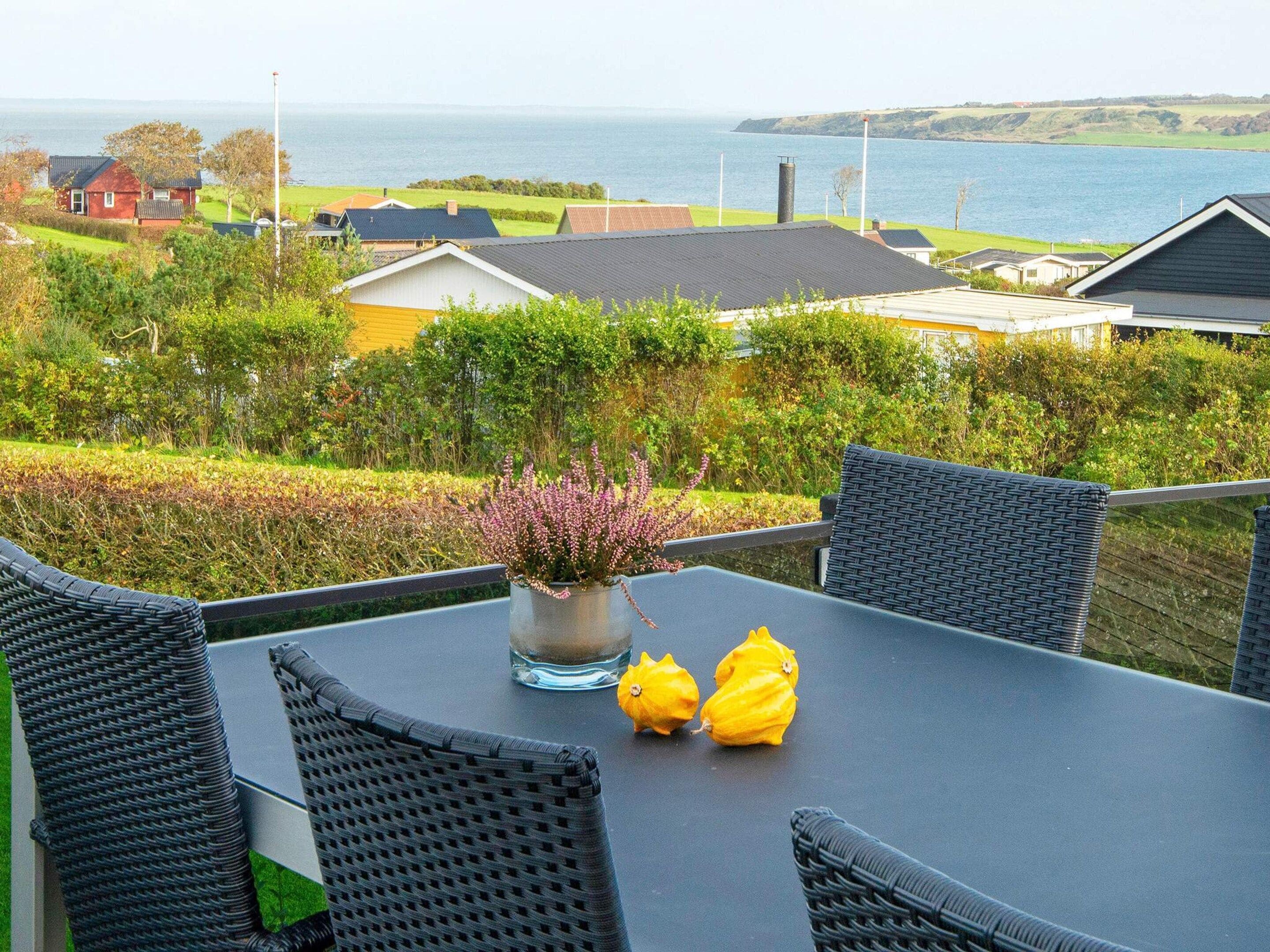 En balkon med fletstole, et bord og en plantepotte.
