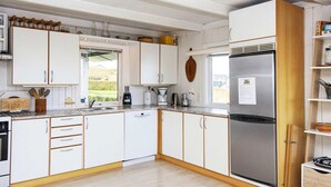 A modern kitchen with white cabinetry, a stainless steel refrigerator, and a window providing a view of the outdoors.