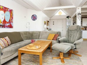 Ein Wohnzimmer mit grauem Sofa, Couchtisch aus Holz und grauem Sessel.