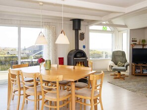 Ein Essbereich mit einem Holztisch und -stühlen, einem Kamin und einem Fernseher in einem Wohnzimmer.