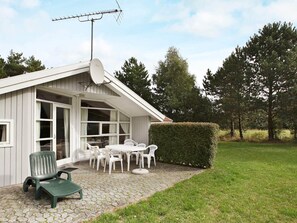 A house with a satellite dish, a patio with a table and chairs, and a hedge. - Quiet Holiday Home in Rodby near Sea (Rodby)