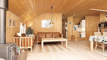 A cozy cabin interior with a wooden interior, a sofa, a dining table, and a fireplace.