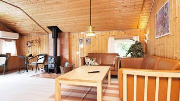 Ein gemütliches Blockhaus-Interieur mit Holzbalkendecke, einer Couch, einem Tisch und einem Kamin.