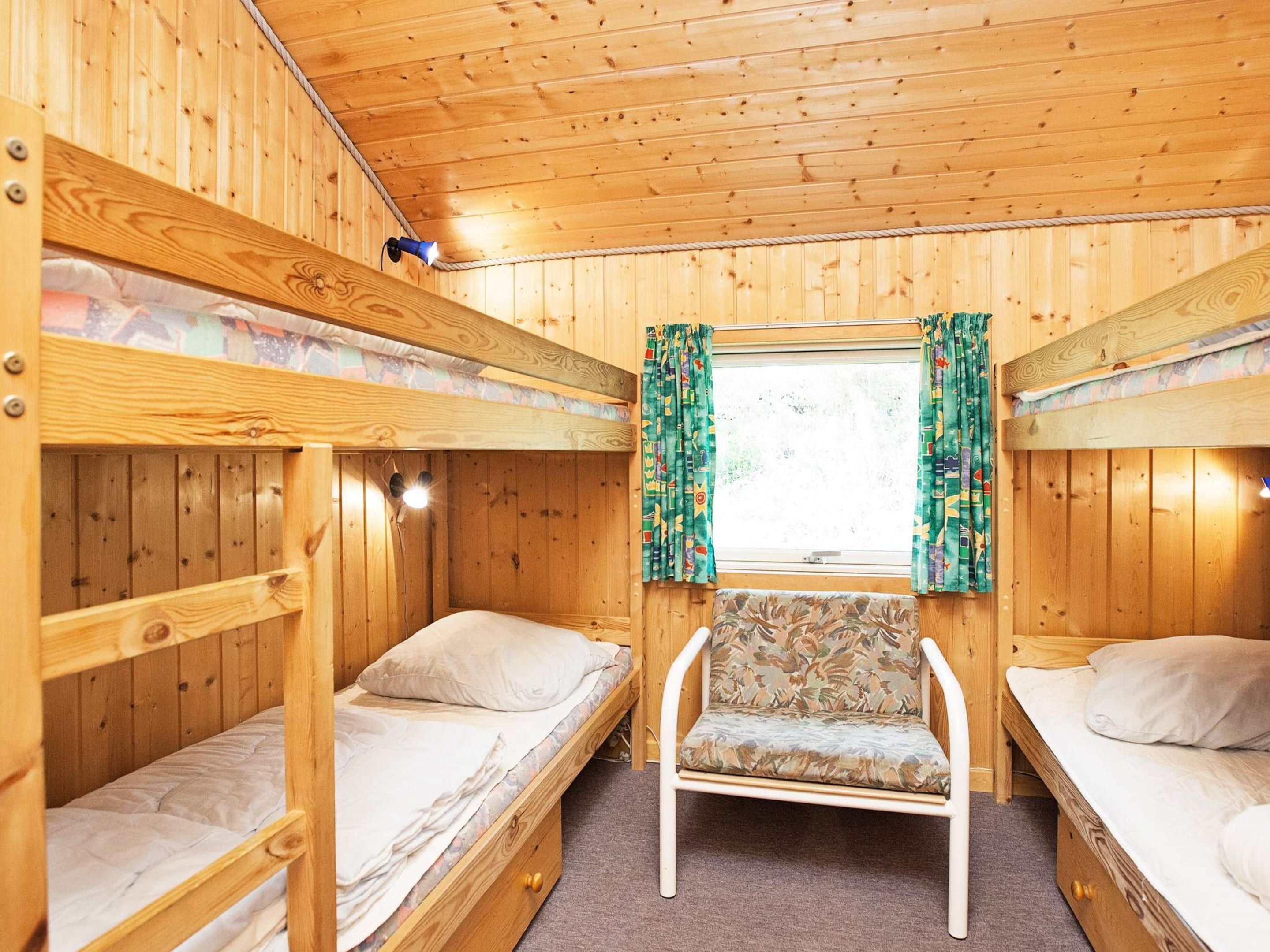A cabin with bunk beds, a central chair, and a window with curtains.