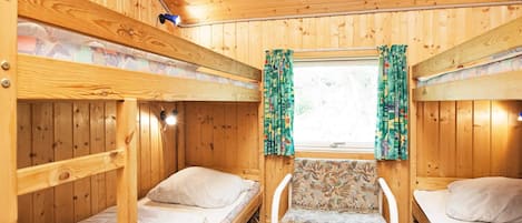 A cabin with bunk beds, a central chair, and a window with curtains.