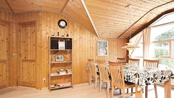 Ein Holzinterieur mit Esstisch, Stühlen, einem Bücherregal und einer Uhr.