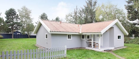 A single-story house with a sloped roof, a porch, and a fenced yard.