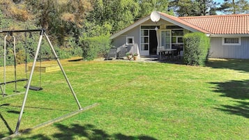 A residential property with a covered patio, outdoor seating, and a swing set.