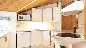 A modern kitchen with wooden ceiling beams, white cabinetry, and a built-in dishwasher.