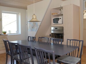 A dining area with a large table and chairs, a hanging light fixture, a map on the wall, and built-in appliances. - Peaceful Holiday Home in Thisted near Sea (Nordborg)