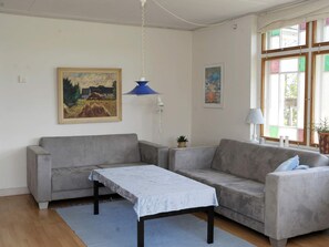 A living room with a grey sofa, a small table, a blue pendant lamp, and two framed paintings on the wall. - Peaceful Holiday Home in Thisted near Sea (Nordborg)