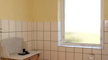 Ein Badezimmer mit Fenster, Waschbecken inklusive Spiegel und Toilette.