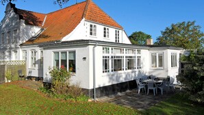A two-story house with a red-tiled roof, large windows, and a patio with outdoor furniture. - Peaceful Holiday Home in Thisted near Sea (Nordborg)