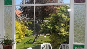 A window with a view of a garden, a wooden structure, and a white chair.