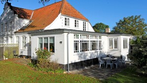 A two-story house with a red-tiled roof, large windows, and a patio area with outdoor furniture. - Peaceful Holiday Home in Thisted near Sea (Nordborg)