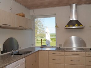 A modern kitchen with a stainless steel range hood, a built-in dishwasher, and a view of a lake and trees. - Peaceful Holiday Home in Thisted near Sea (Nordborg)