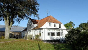 A white building with a red-tiled roof, a large tree, and a clear blue sky. - Peaceful Holiday Home in Thisted near Sea (Nordborg)