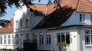 A two-story building with a red-tiled roof, white walls, and multiple windows.
