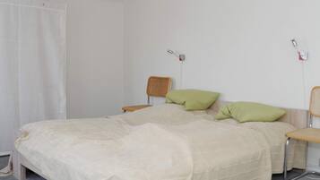 A bedroom with a bed, a chair, and a bedside table.